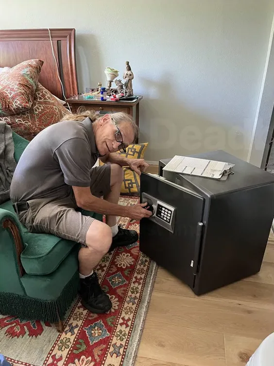 Jack Mathes kneeling beside a keypad fire safe in a customer's bedroom during a safe call
