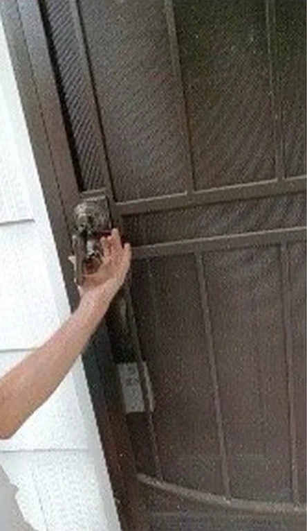Hand on the lock of a steel security screen door at a Portland home